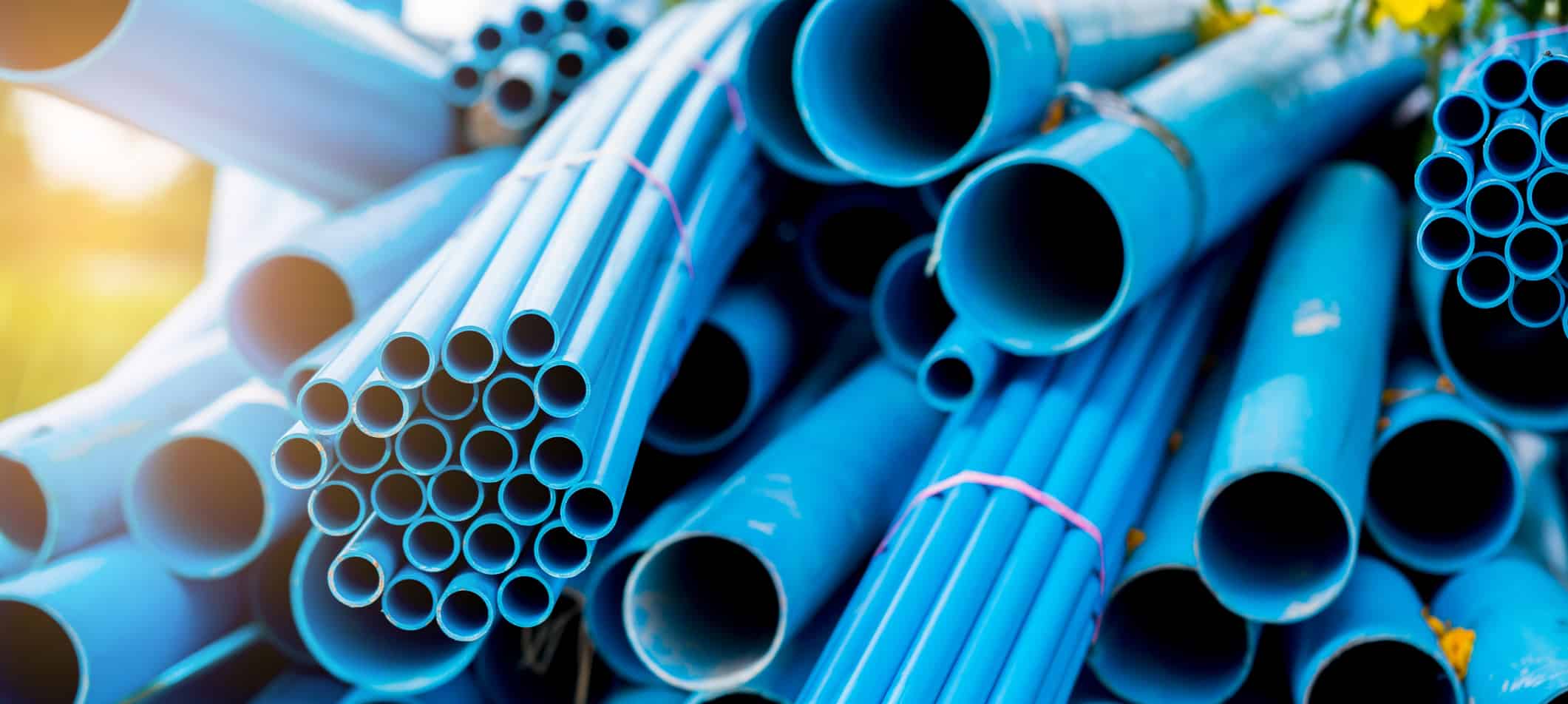 Selective to blue plastic pipe background. PVC pipes stacked in warehouse of construction site.  PVC water pipes used for construction.