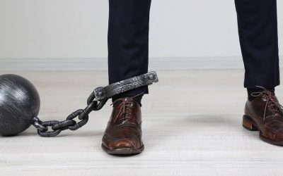 Business worker with ball and chain attached to foot