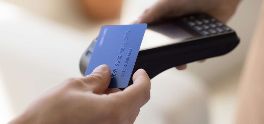 Close up crop view unknown male makes easy, convenient e-payment, holds plastic card against contactless payment terminal equipment, paying for services, food or shopping use wireless NFC technology