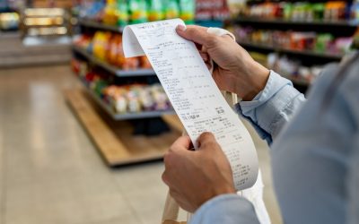 Close-up on a woman shopping at a convenience store and checking her receipt while exiting