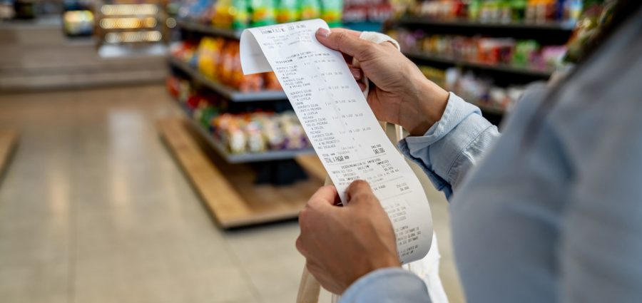 Close-up on a woman shopping at a convenience store and checking her receipt while exiting
