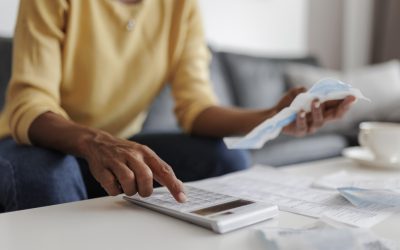 Close up of a mid adult woman checking her energy bills at home, sitting in her living room. She has a worried expression