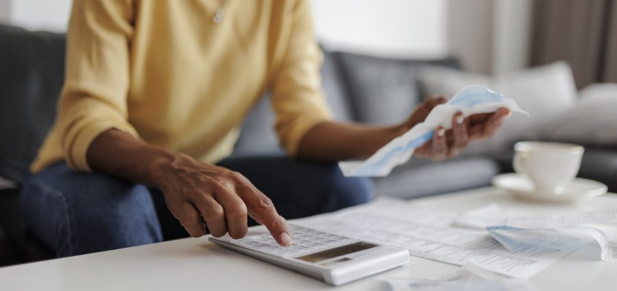 Close up of a mid adult woman checking her energy bills at home, sitting in her living room. She has a worried expression