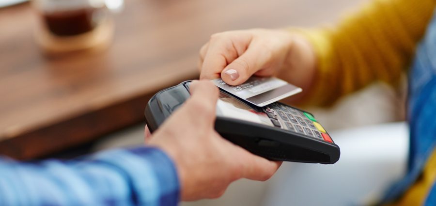 Close-up of unrecognizable customer choosing contactless payment using credit card while waitress accepting payment over nfc technology