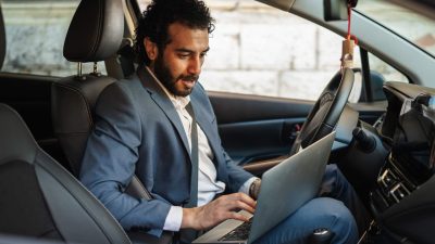 Entrepreneur working from his car, focused on a laptop while managing calls and emails on the gomodern mobile office lifestyle showcasing remote work productivity and connectivity