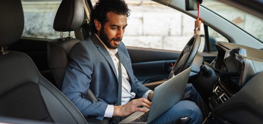 Entrepreneur working from his car, focused on a laptop while managing calls and emails on the gomodern mobile office lifestyle showcasing remote work productivity and connectivity
