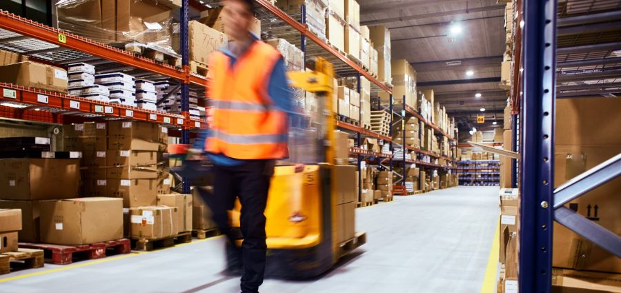 Warehouse, worker with a forklift in motion blur.