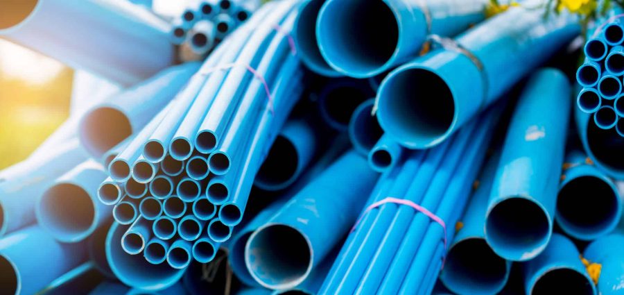 Selective to blue plastic pipe background. PVC pipes stacked in warehouse of construction site.  PVC water pipes used for construction.