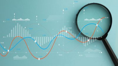 Magnifying glass over digital data graph and charts. Business analytics, financial market research, and statistics concept. Stock market, investment, and data audit.