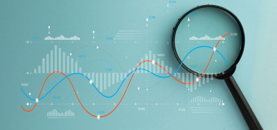 Magnifying glass over digital data graph and charts. Business analytics, financial market research, and statistics concept. Stock market, investment, and data audit.