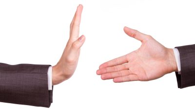 Businessman hands, one of reaching for handshake, the other gesturing stop sign, isolated on white background.