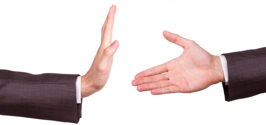 Businessman hands, one of reaching for handshake, the other gesturing stop sign, isolated on white background.