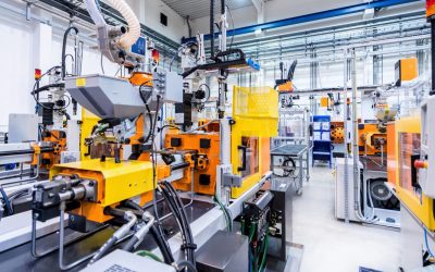 Horizontal color image of large group of automated injection moulding machines for plastic parts production.