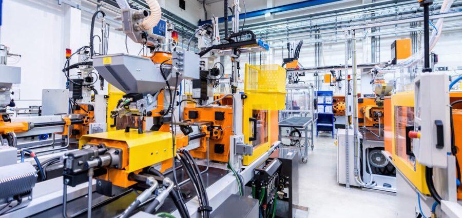 Horizontal color image of large group of automated injection moulding machines for plastic parts production.