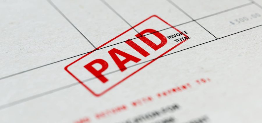 Close-up picture of an invoice with red paid stamp with selective focus. Great use for financial concepts.