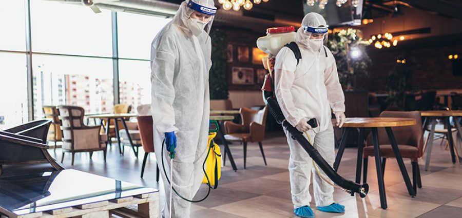 Professional workers in hazmat suits disinfecting indoor of cafe or restaurant, pandemic health risk, coronavirus